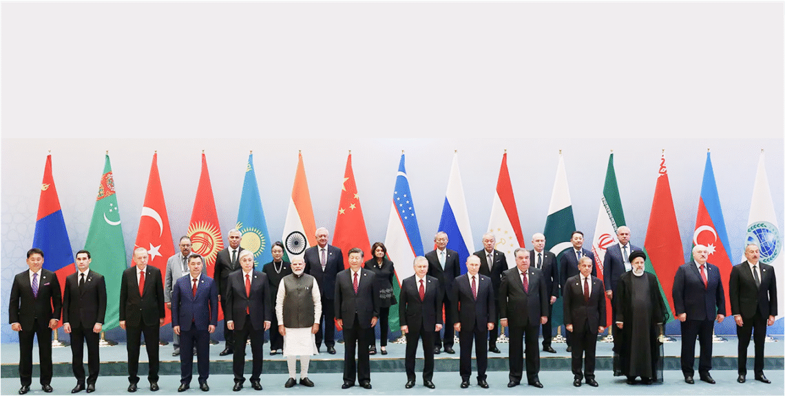 World leaders at the SCO Summit 2025 standing for a group photo with national flags in the background