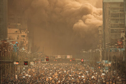 Massive crowd of protesters on Tehran's Ayatollah Kashani Boulevard at night, illuminated by mobile phone lights and fires.